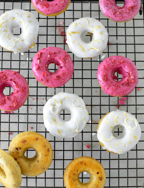 strawberry glazed and lemon glazed doughnuts on a cooling rack.