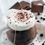 italian hot chocolate in clear glass cup with napkin and chocolate pieces in te background, image for pinterest