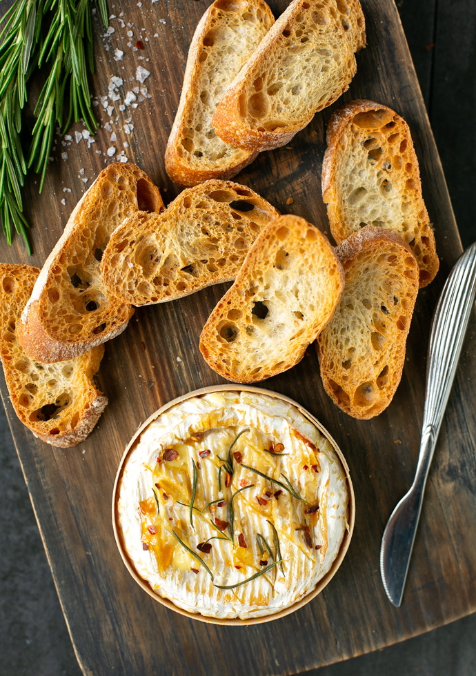 baked camembert in wooden box topped with rosemary, honey and chilli flakes, served with toasted bread.