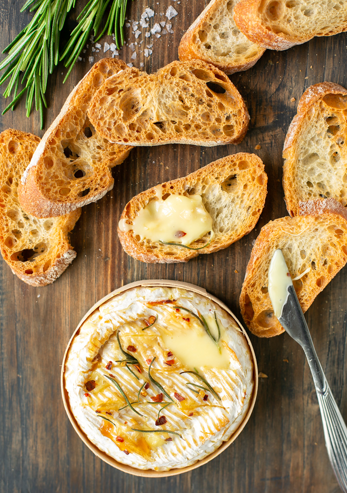 baked camembert in wooden box serve with toasted baguette slices.