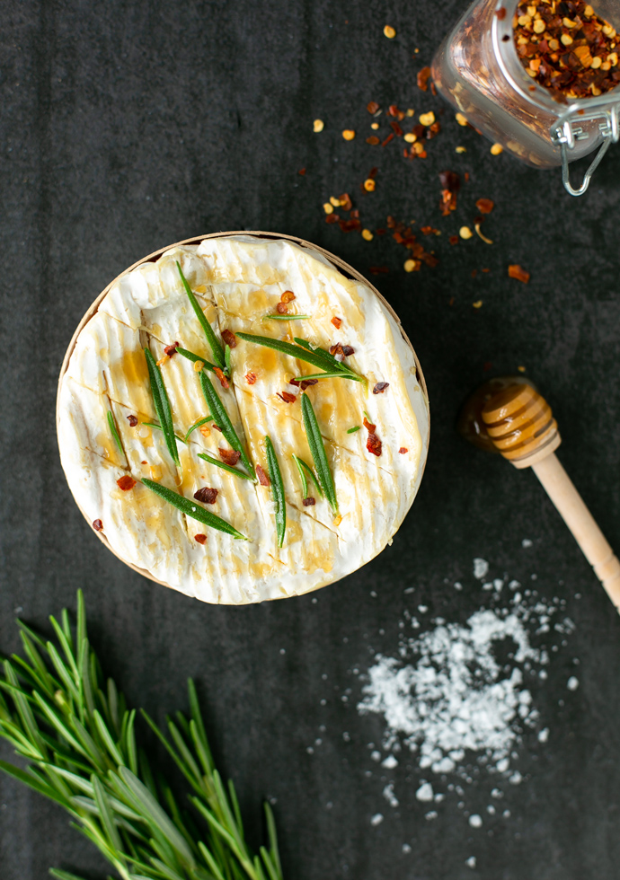 Camembert cheese in its wooden box, topped with rosemary, sea salt honey and chilli flakes.