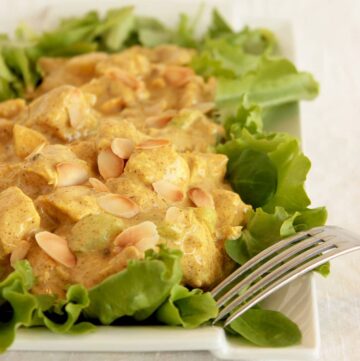 coronation chicken topped with toasted almond flakes on a bed of salad leaves
