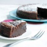 2-ingredient nutella cake slice in the focus with fork next to it, cake in the background on a turquoise plate.