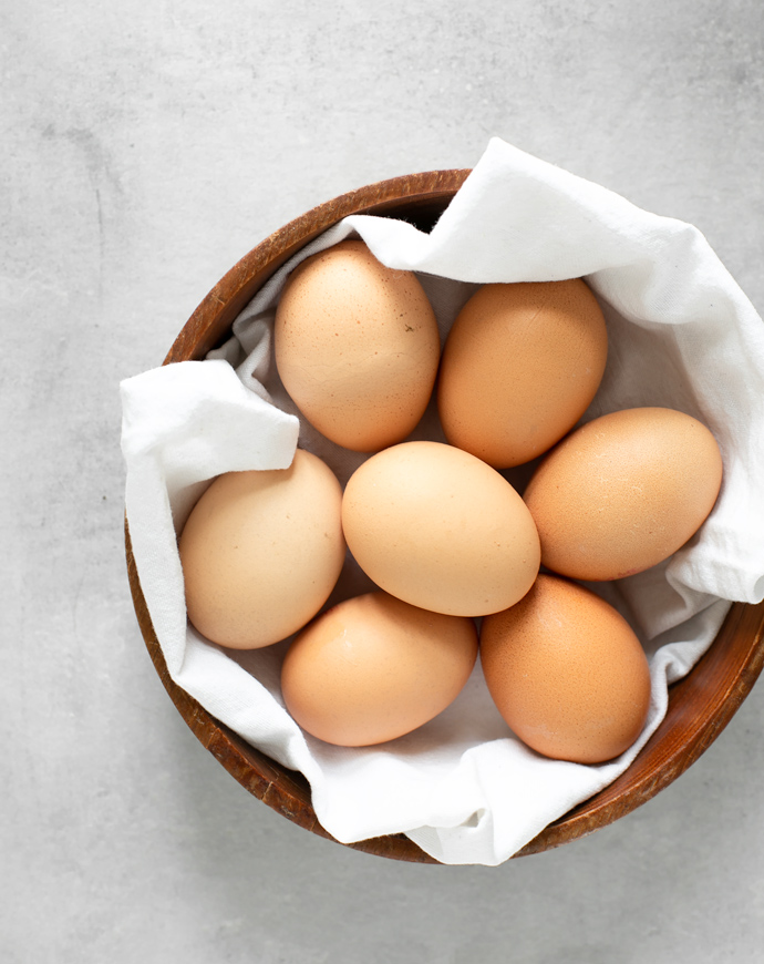 eggs in a wood bowl covered with a white napkin