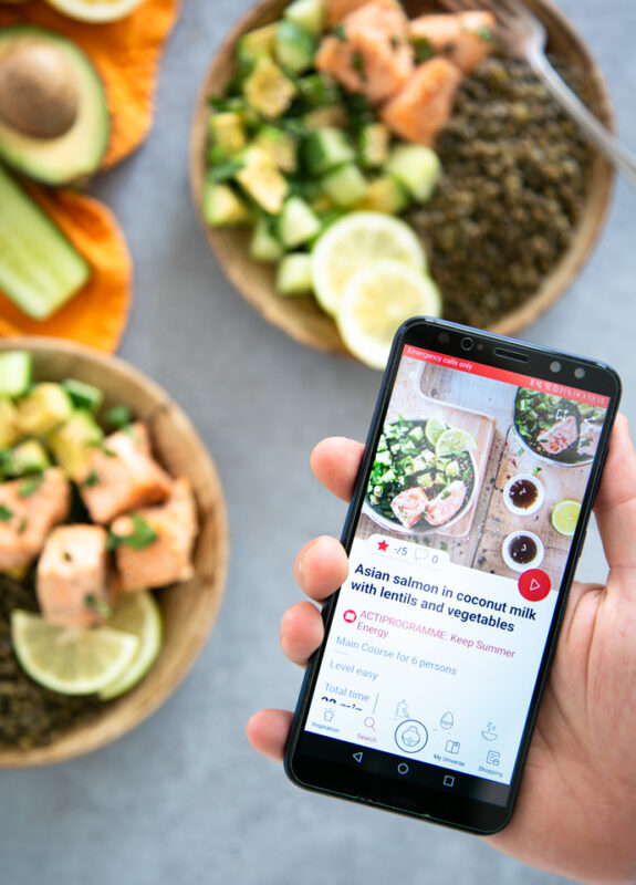 hand holding phone with recipe for the air fryer salmon, in the background the dish prepared in two wood plates