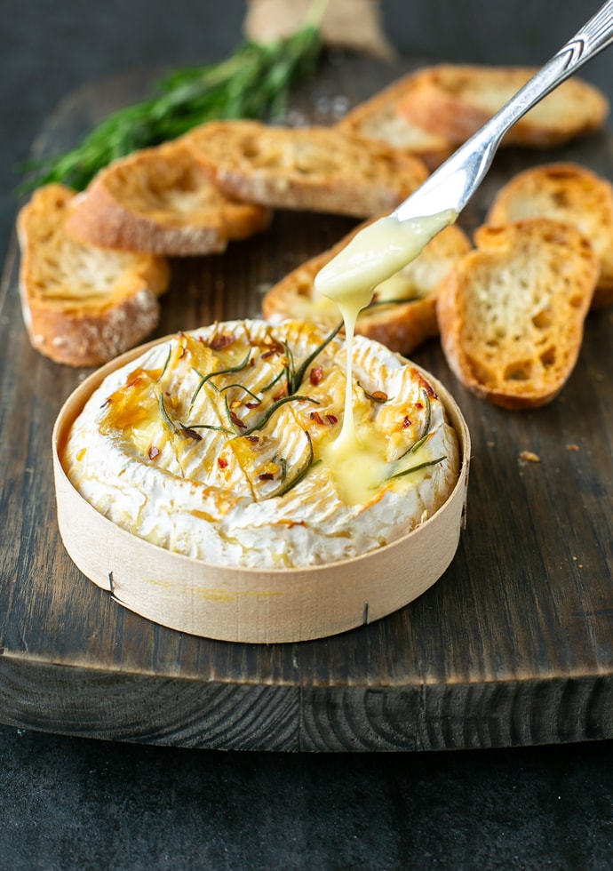 baked camembert in wooden box served with toasted bread.