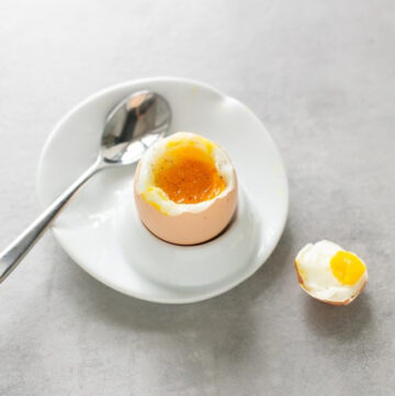 soft boiled egg on a plate next to a spoon