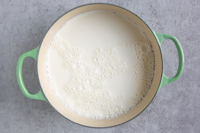 milk in a large cast iron pot with green handles