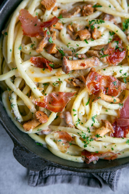 bucatini with prosciutto and chanterelle mushroom in a cast iron skillet