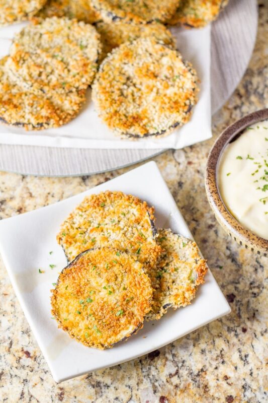 crispy eggplant slices divided among two plates, served with lemon aioli