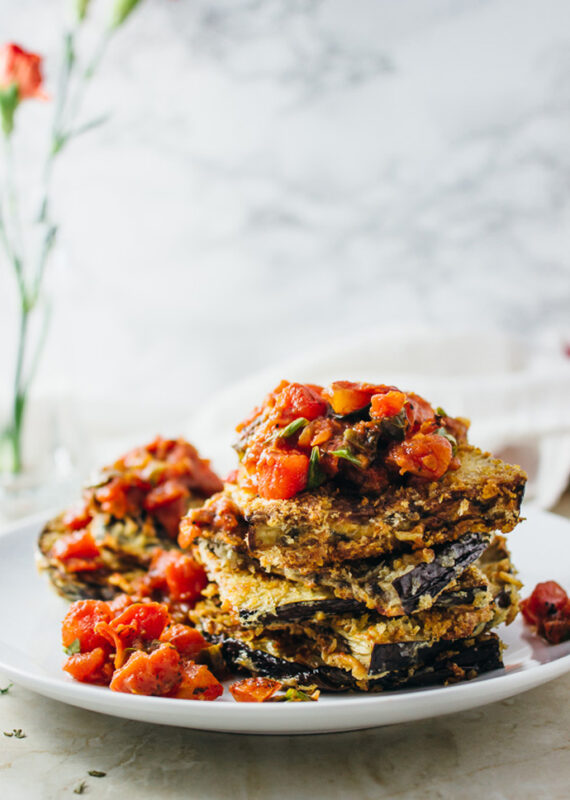 stack of crispy eggplant slices topped with chunky tomato sauce