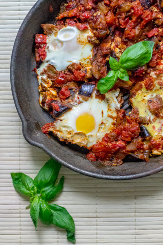 eggplant shakshuka topped with eggs ina cast iron skillet