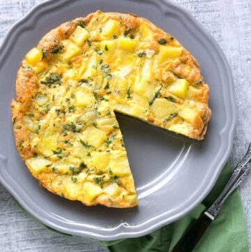 potato frittata with one slice cut away, on a grey plate
