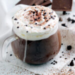 thick italian hot chocolate in a clear mug topped with whipped cream and chocolate shavings