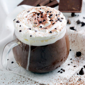 thick italian hot chocolate in a clear mug topped with whipped cream and chocolate shavings
