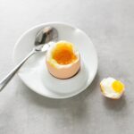soft boiled egg on a plate next to a spoon