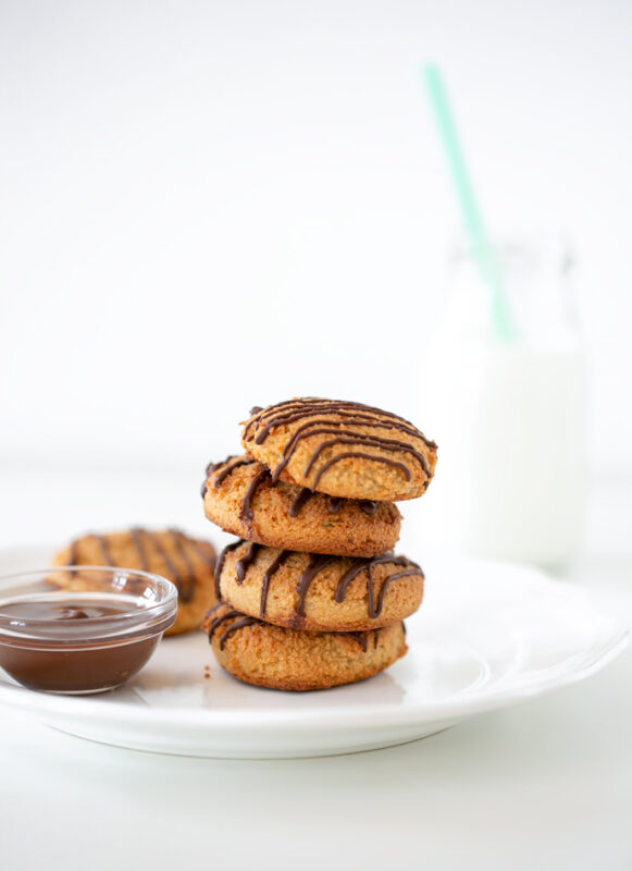 4 cookies served on top of each other on a plate with melted chocolate and milk on the side