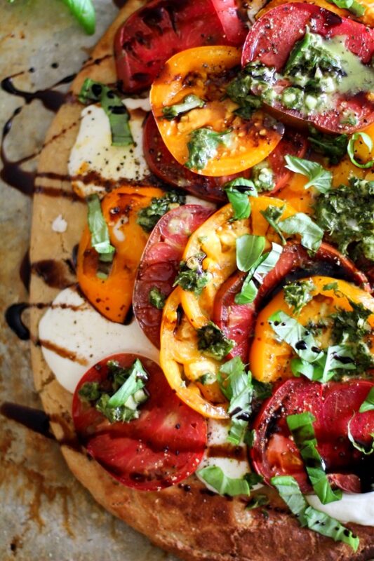 Almond flour pizza base topped with tomatoes, mozzarella and chimichurri sauce