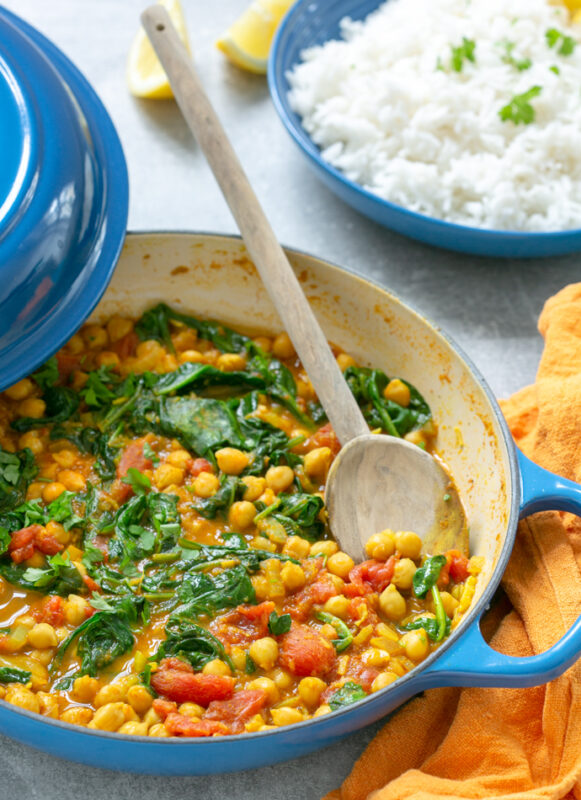spinach and chickpea curry in a large pot, served with rice on the side