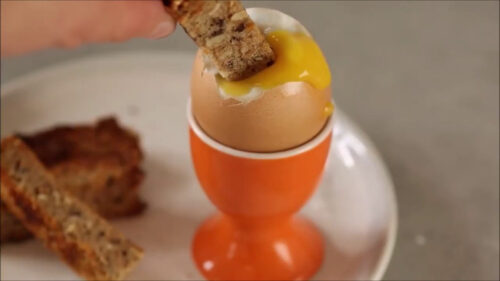 soft boiled egg in a egg cup with toasted bread dipped in