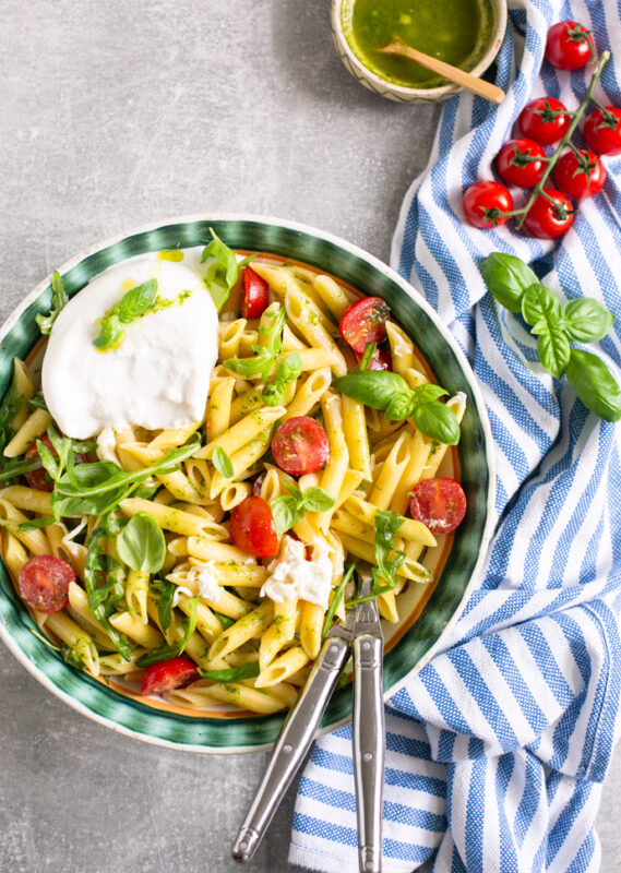 burrata pasta salad served in a big bowl with serving spoons.