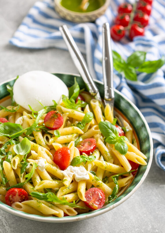 burrata pasta salad served in a big bowl with serving spoons.