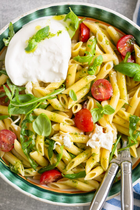 burrata pasta salad served in a big bowl with serving spoons.