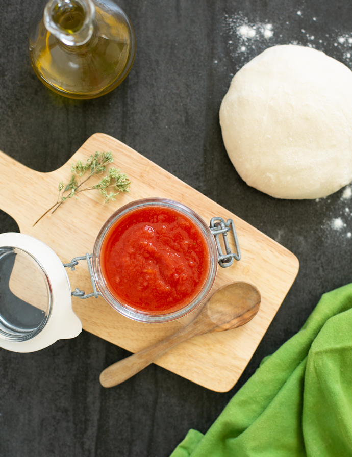 homemade pizza sauce in a jar, pizza dough, bottle of olive oil, oregano.