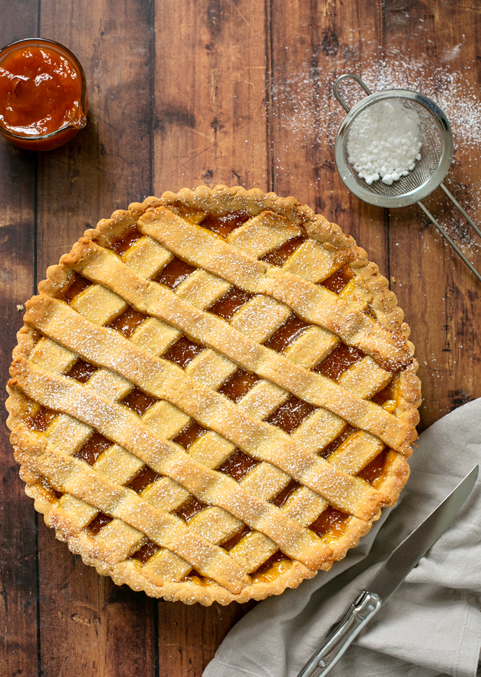 crostata with jam with confectioner sugar and peach jam on the side.