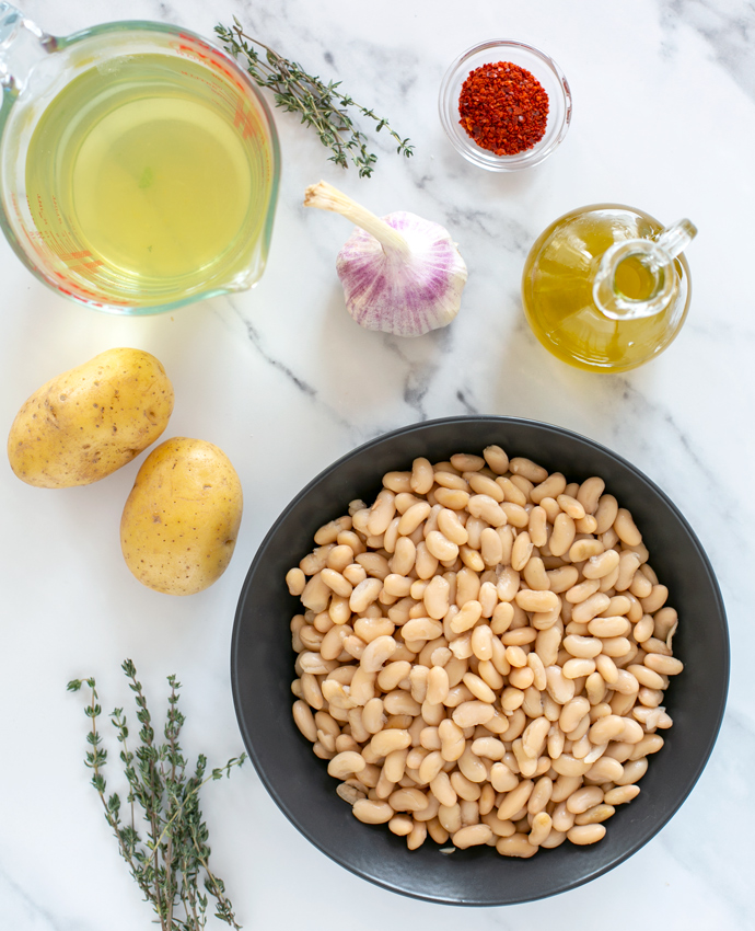 recipe ingredients: vegetable broth, thyme leaves, garlic, extra-virgin olive oil, cannellini beans, potatoes and red chili flakes.