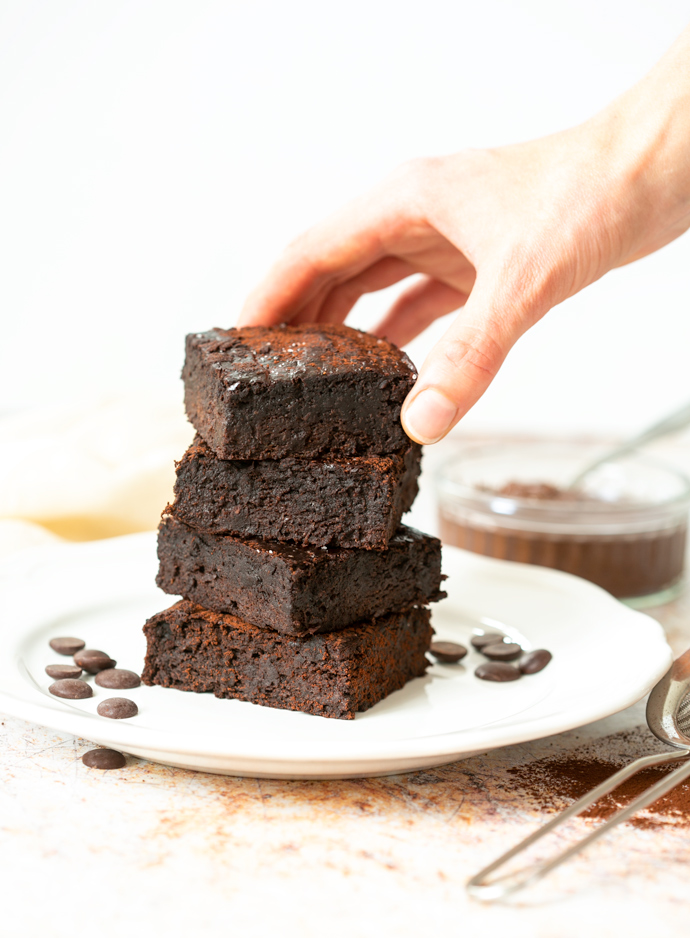 hand grabbing a brownie at the top of other 3 brownies.