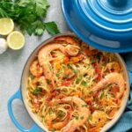 linguine with prawns in a shallow casserole pot, topped with chopped parsley and whole king prawns. Image for Pinterest.