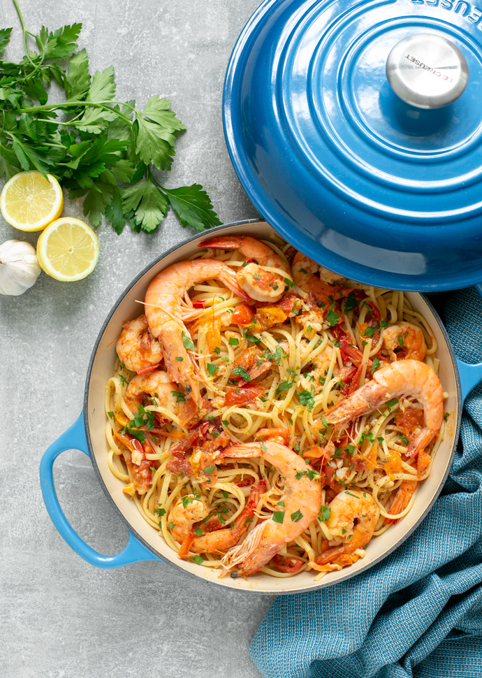 prawn linguine in a shallow casserole pot, topped with chopped parsley and whole king prawns.