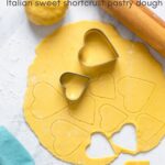 italian sweet shortcrust pastry dough rolled into a disk and cut with heart-shaped cookie cutters. Image optimized for Pinterest.