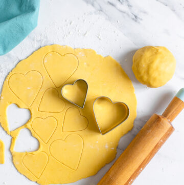 italian sweet shortcrust pastry dough rolled into a disk and cut with heart-shaped cookie cutters.