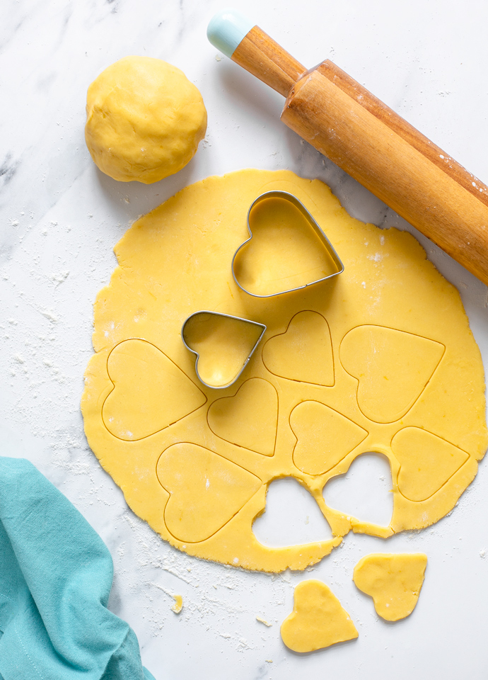 italian sweet shortcrust pastry dough rolled into a disk and cut with heart-shaped cookie cutters.