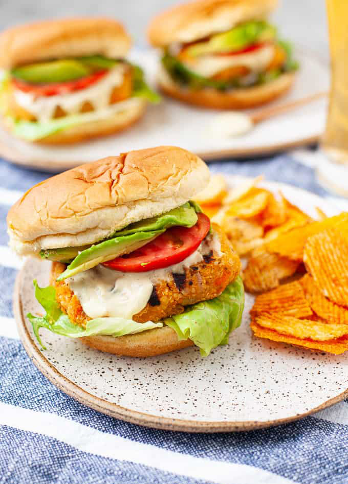 buffalo chickpea burger with lettuce, dressing and tomatoes, served with chips.