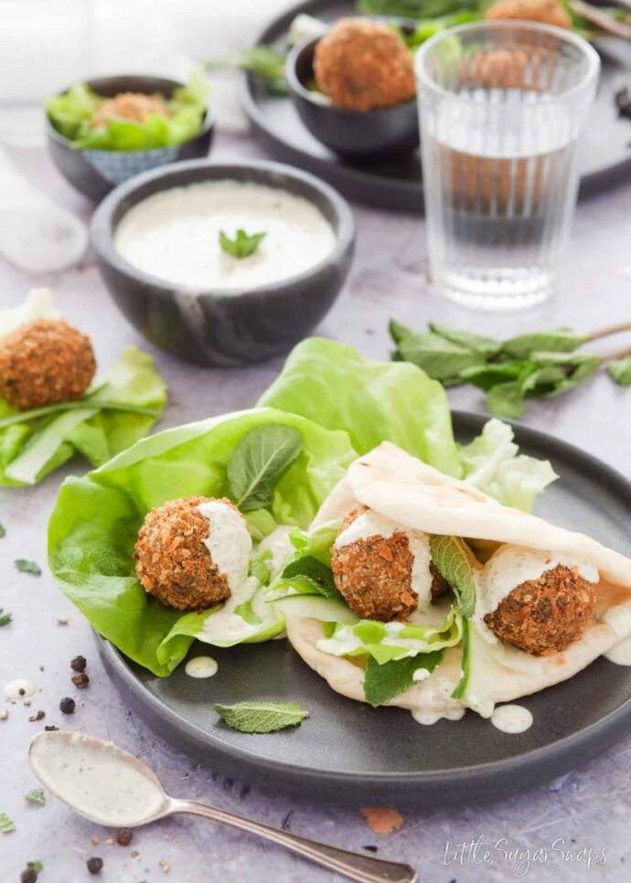 Mint pea falafels with lettuce in pita bread topped with dressing.
