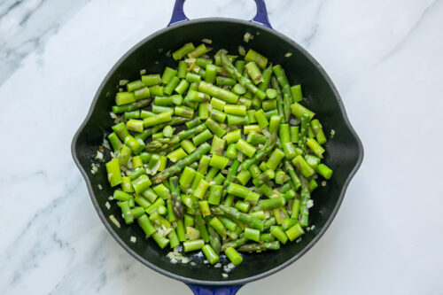 asparagus and onion sauteed in a skillet.
