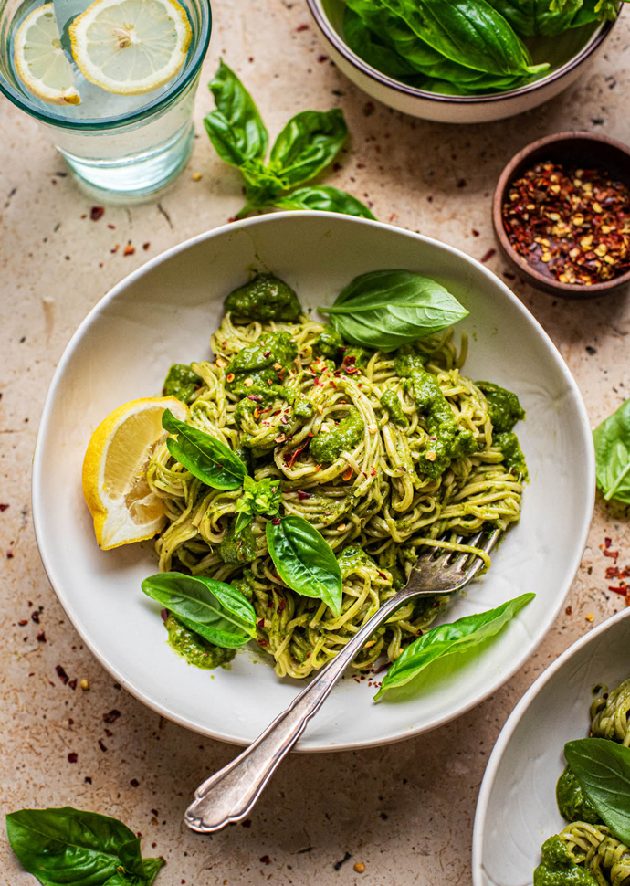 spaghetti with vegan green veggie sauce topped with basil leaves.