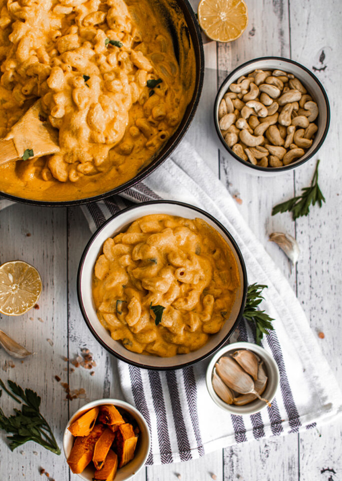 vegan pumpkin mac and cheese dividided among a large skillet and a bowl.