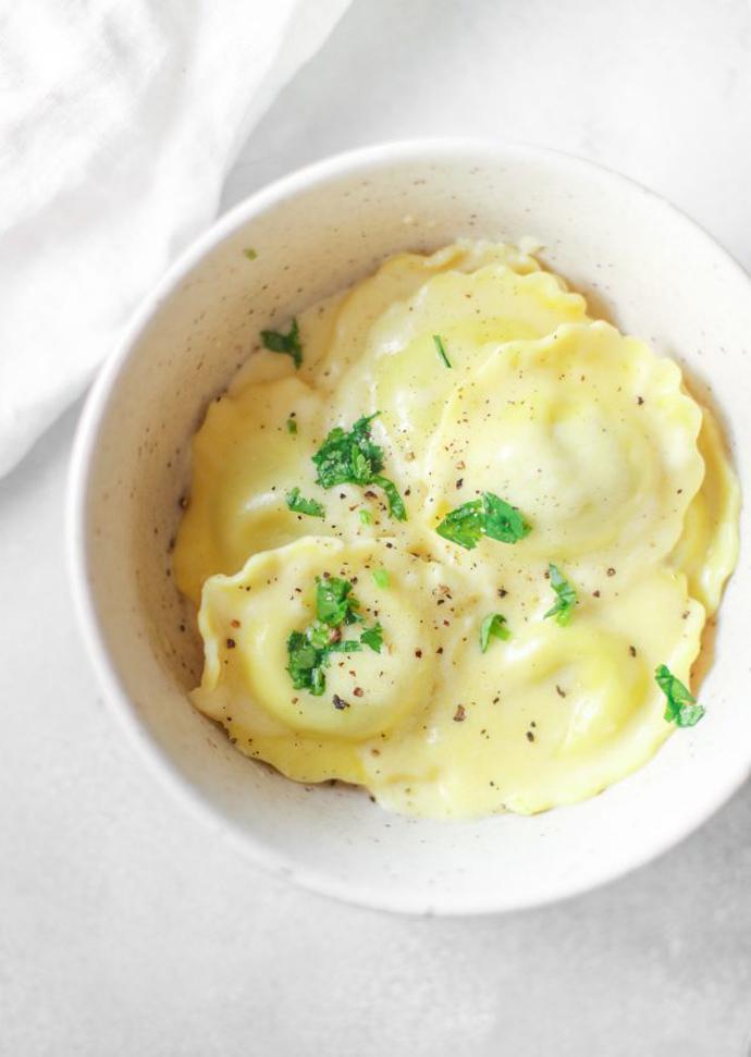 ravioli topped with fresh herbs on a plate.