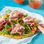 Gluten-free chickpea pizza with Parma ham, rocket leaves and sliced cherry tomatoes. Image for Pinterest.