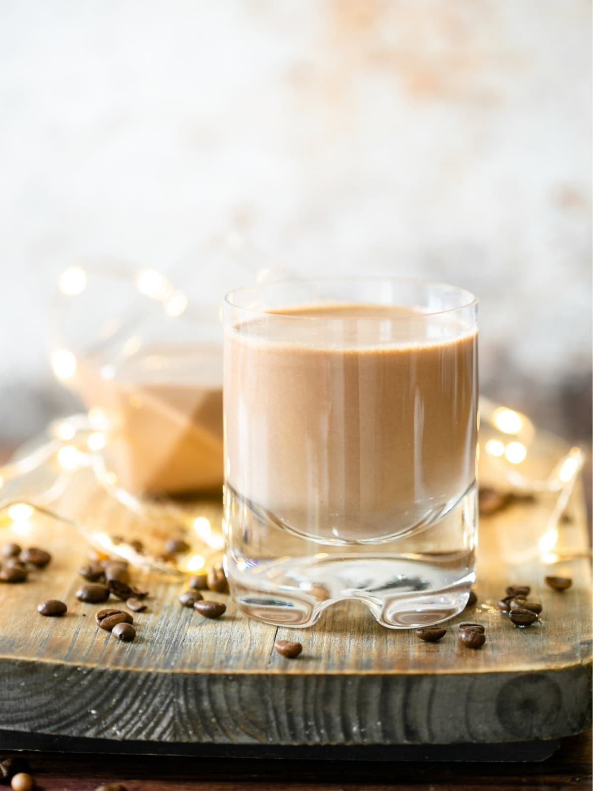 Glass of homemade Irish cream liqueur over ice on a wooden board