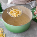 penne pasta cooked al dente in a colander over a pot with pasta.