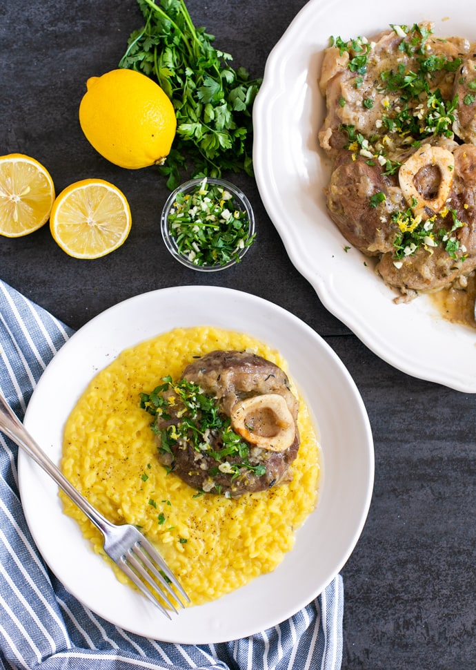 ossobuco alla milanese served over a bed of saffron risotto, and topped with gremolata.