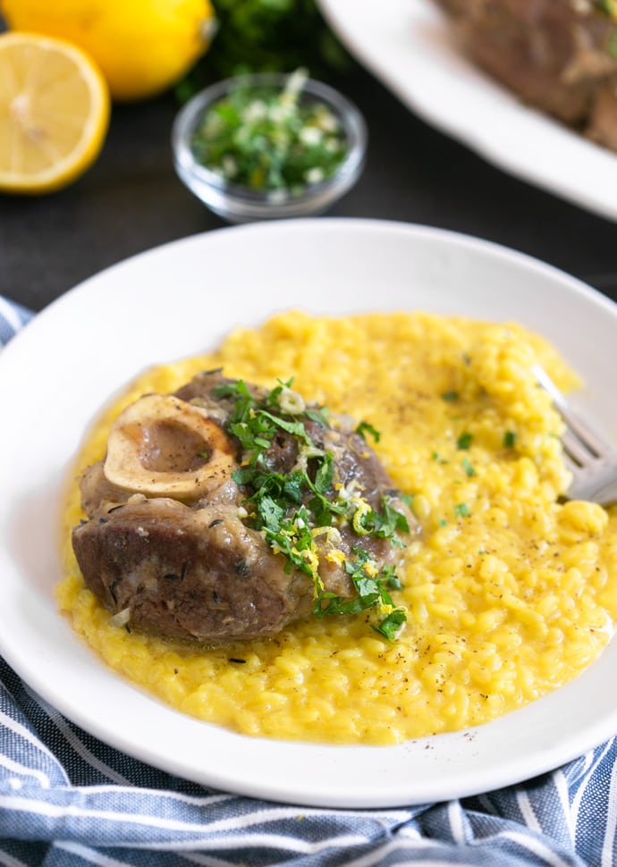 ossobuco alla milanese served over a bed of saffron risotto, and topped with gremolata.