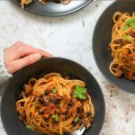 vegan spaghetti bolognese divided among three bowls. Image with text for Pinterest.