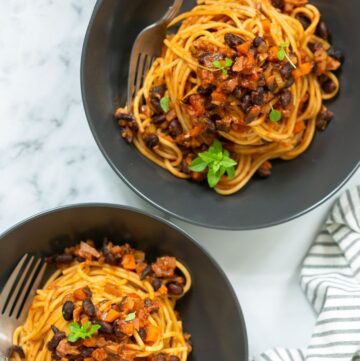 vegan spaghetti bolognese divided among two bowls.