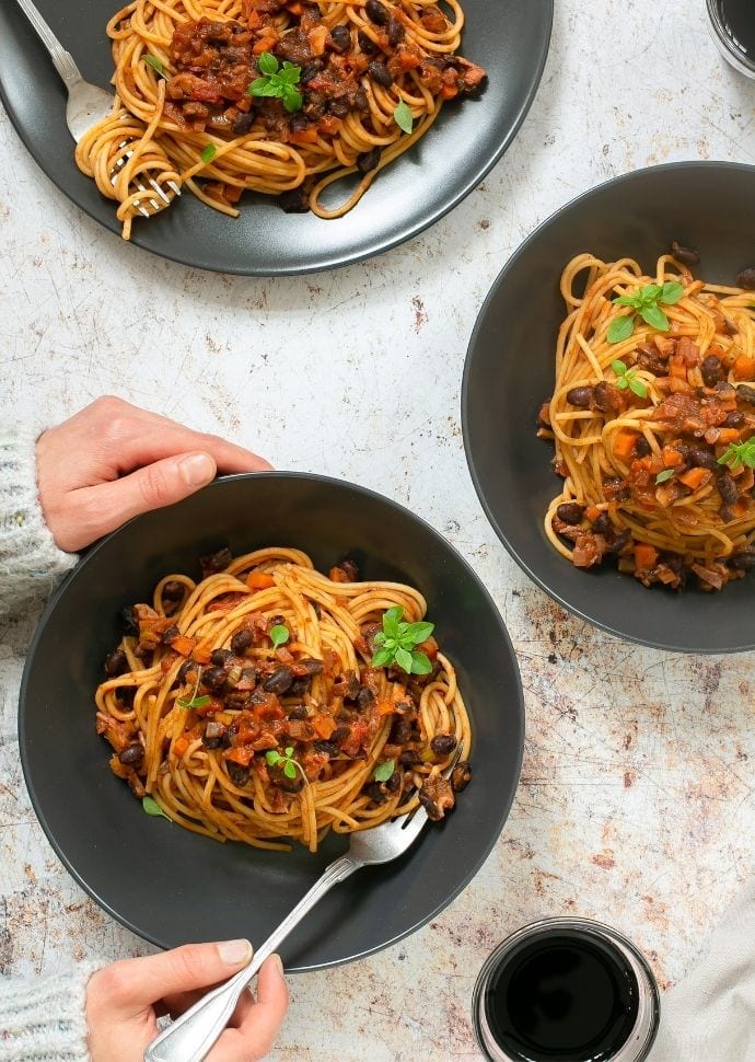 vegan spaghetti bolognese divided among three bowls.